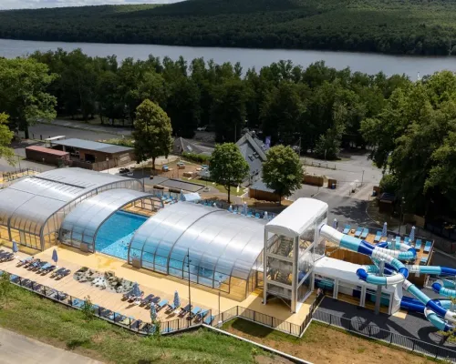 Vue d'ensemble de la piscine avec toboggans et chaises longues au camping Roan Le Lac des Vieilles Forges.