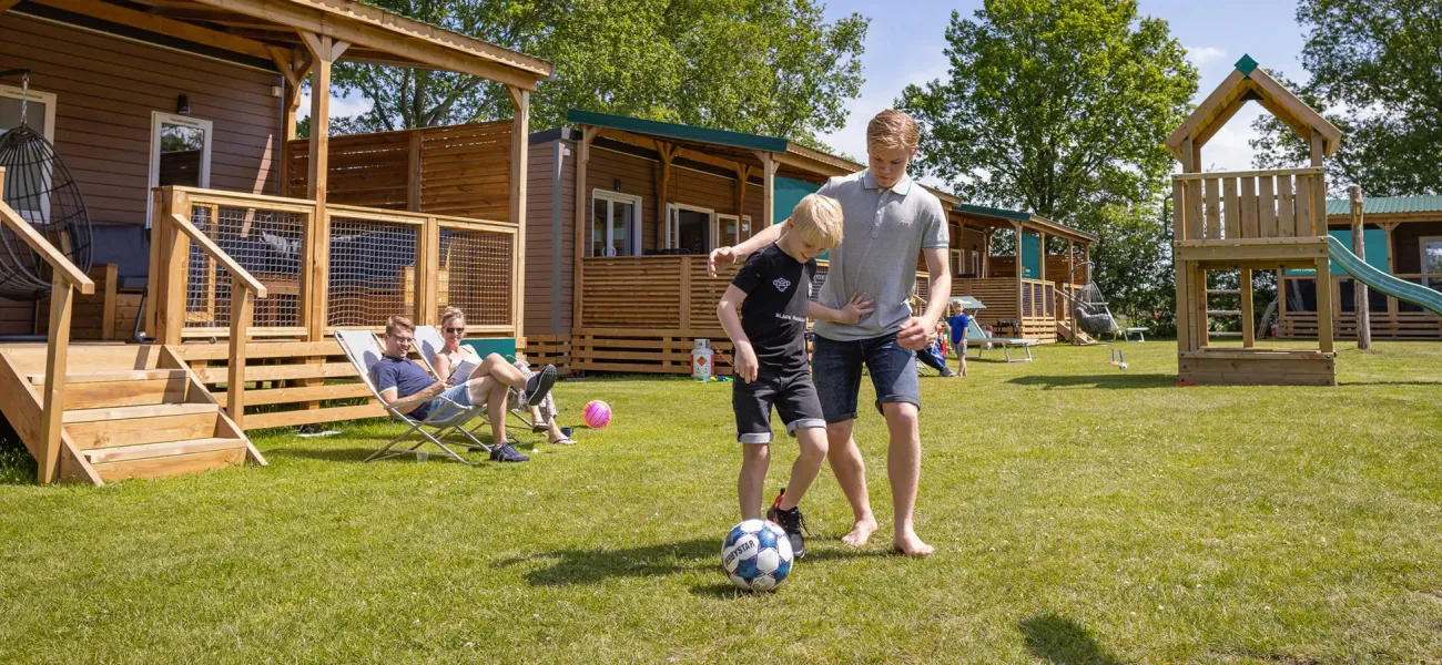 Des enfants jouent au football devant un mobile home dans un camping de Roan.